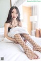 A woman in fishnet stockings sitting on a bed.