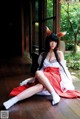 A woman in a red and white dress sitting on a wooden floor.