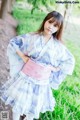 A woman in a blue and white kimono standing in the grass.