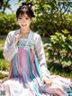 A woman in a blue and pink hanbok sitting on the ground.