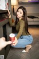 A woman sitting on the floor next to a vending machine.