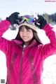 A young woman in a pink jacket and ski goggles.