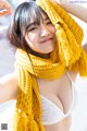 A woman wearing a yellow scarf and a white bra.