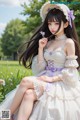 A woman in a white dress and hat sitting in a field of flowers.