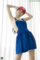 A woman in a blue dress and a red hat posing for a picture.