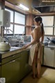 A woman standing in a kitchen next to a sink.