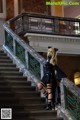 A woman in a black dress is standing on some stairs.