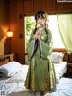 A woman in a green kimono standing on a bed.