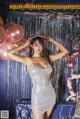 A woman in a silver dress posing in front of balloons.