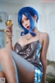 A woman with blue hair holding a glass of wine.