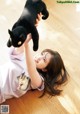 A woman laying on the floor holding a black cat.