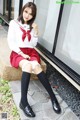 A woman in a school uniform sitting on a ledge.