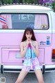 A woman standing in front of a pink and white van.