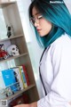 A woman with blue hair wearing a white lab coat and glasses.