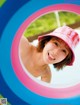 A young girl in a pink hat smiles through a colorful ring.