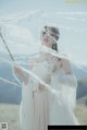 A woman in a white dress holding an umbrella.