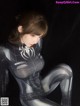 A woman in a black and white spider suit sitting on the ground.