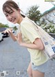 A woman in shorts and a yellow shirt holding a bag.