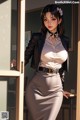 A woman in a skirt and blazer leaning against a door.