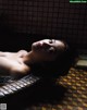 A woman laying in a bathtub with her eyes closed.