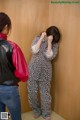 A woman in pajamas standing in front of a wooden wall.