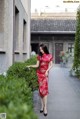 A woman in a red dress is walking down a sidewalk.